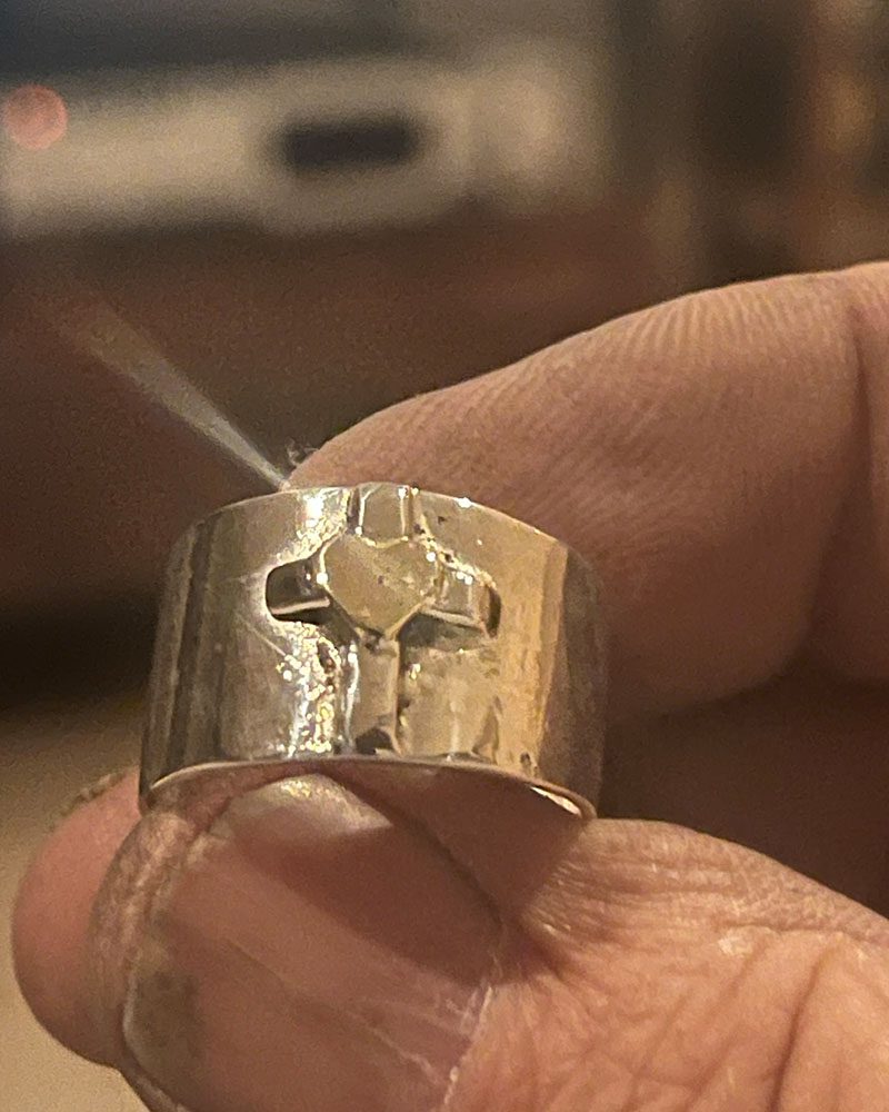 A person holding a silver ring with a cross on it.
