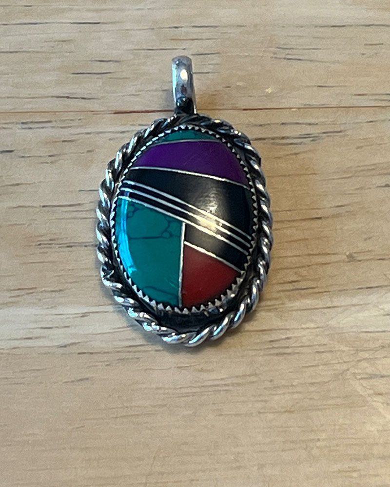 A silver pendant with a colorful stone on it.
