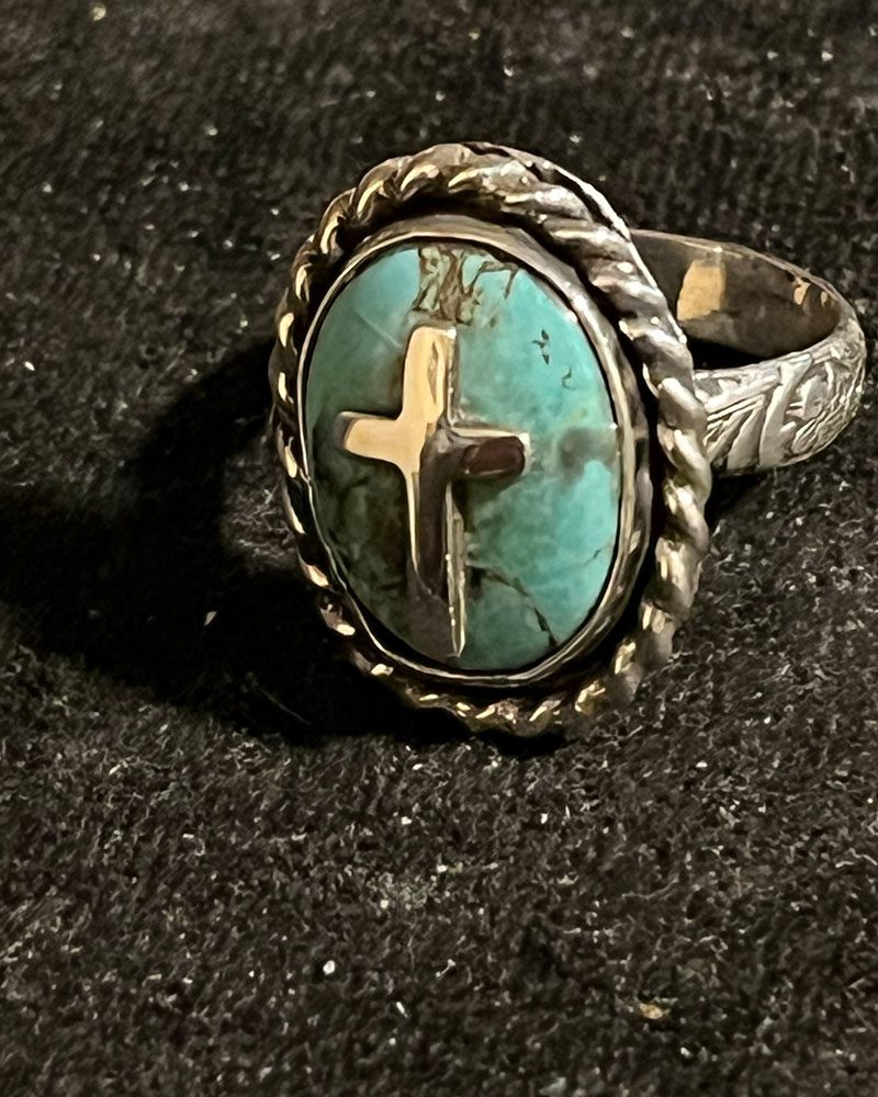 A turquoise ring with a cross on it.