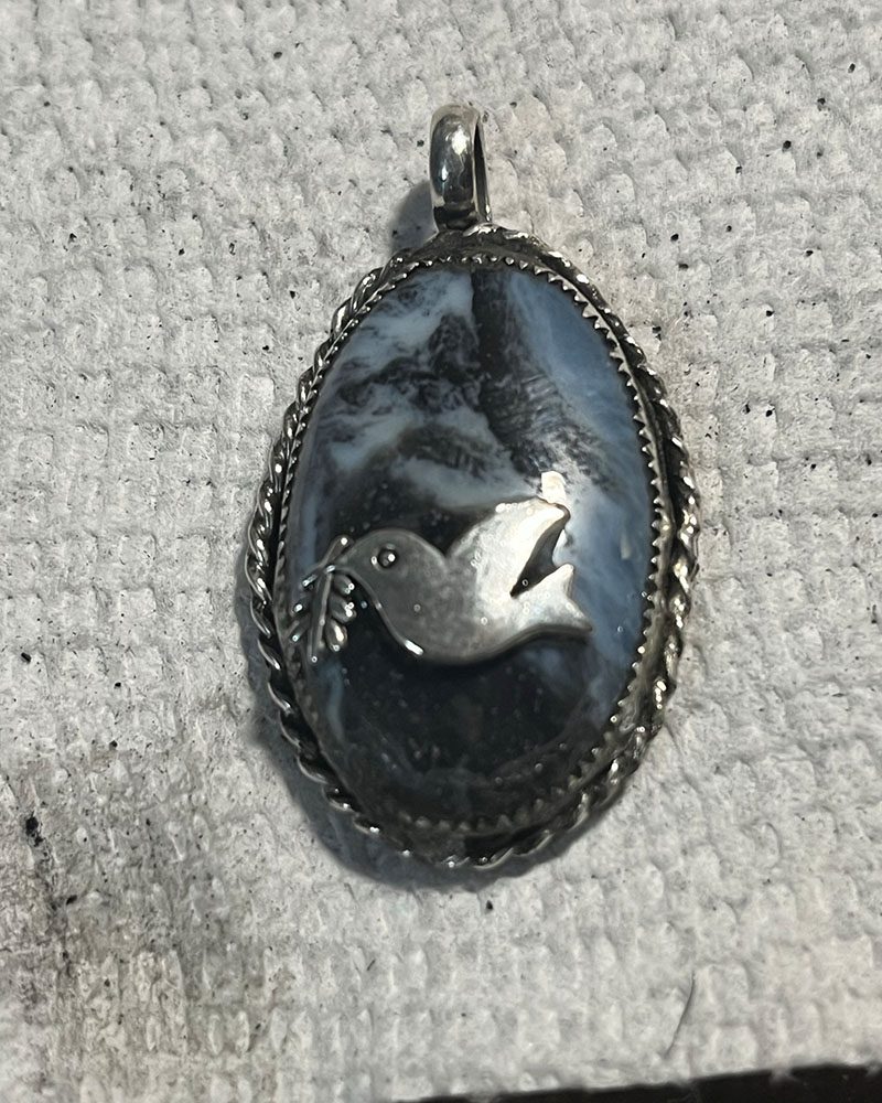 A silver bird on top of a blue stone.