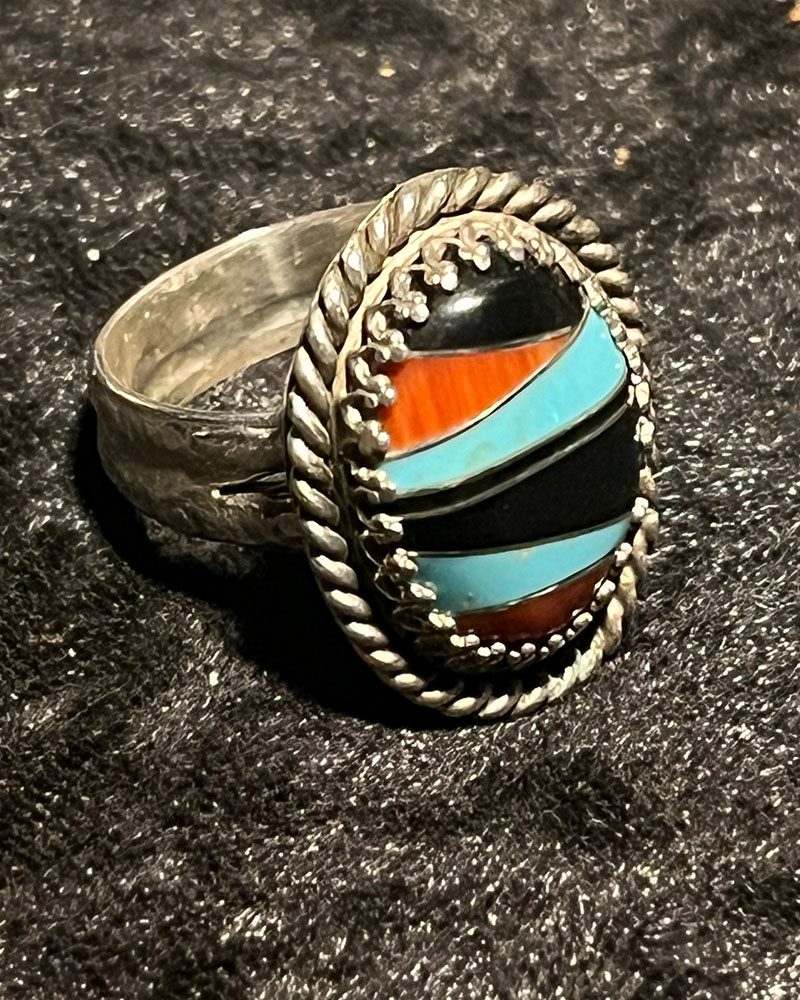 A silver ring with a colorful stone on it.