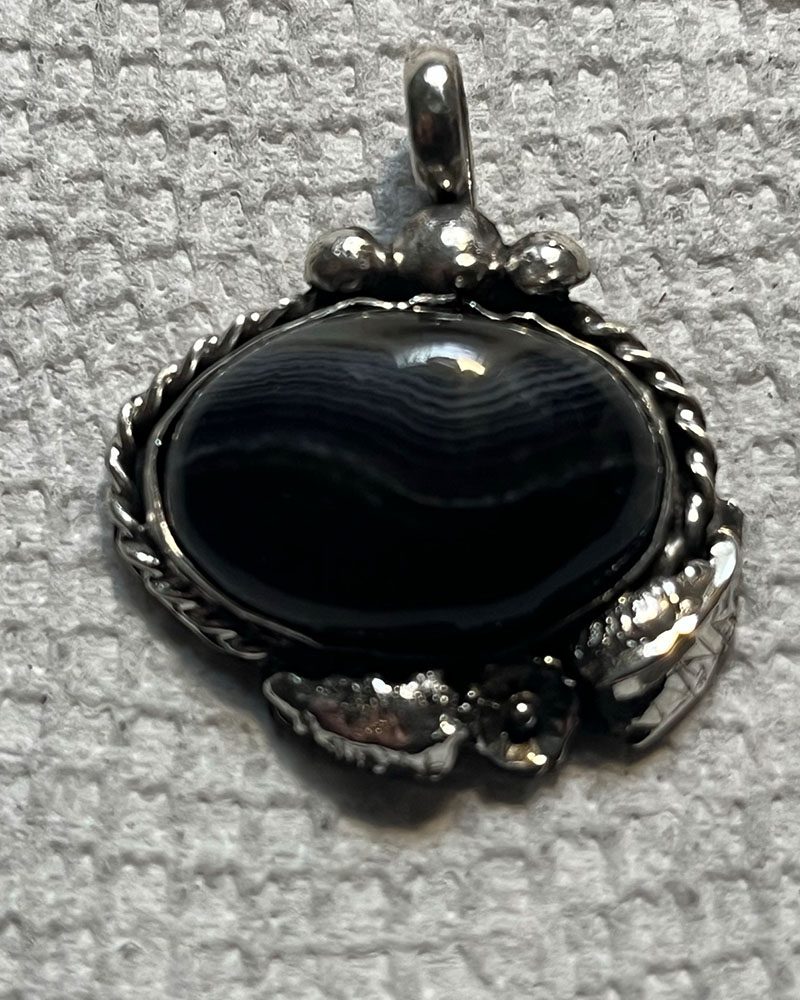 A black stone is in the middle of a silver frame.