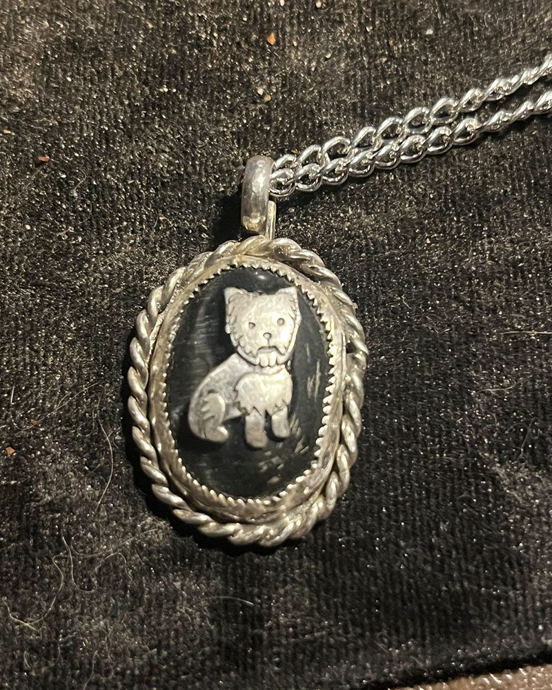 A silver necklace with a picture of a cat on it.