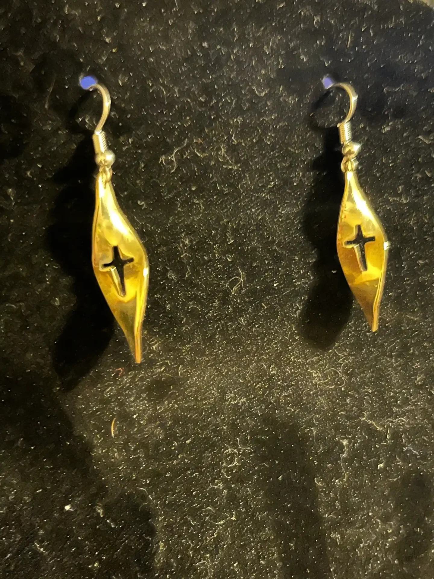 A pair of gold earrings with black cross on them.