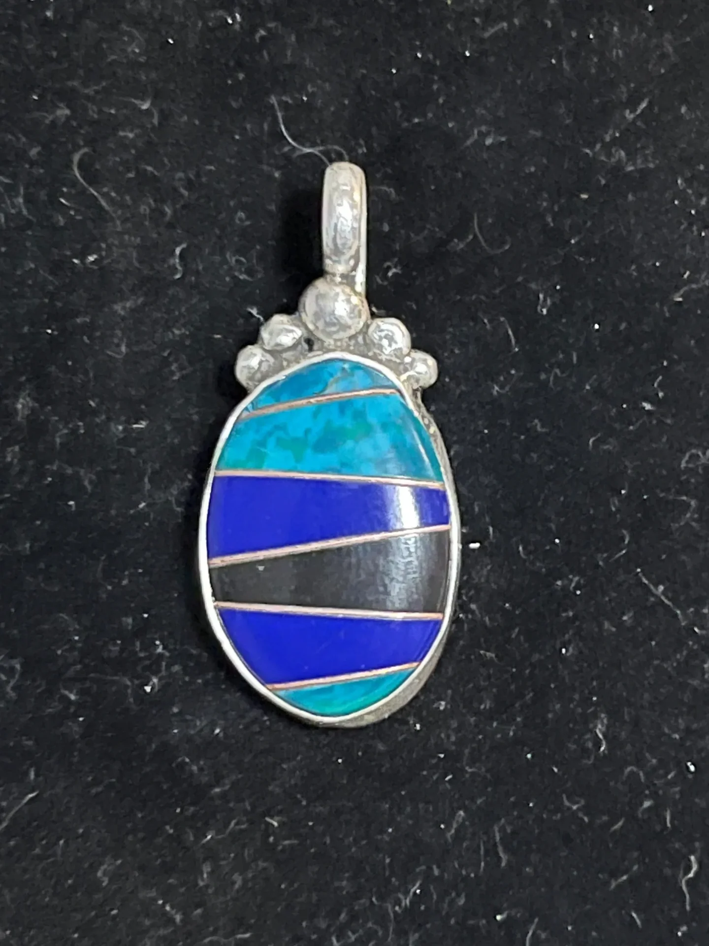 A blue and black pendant is shown on the ground.