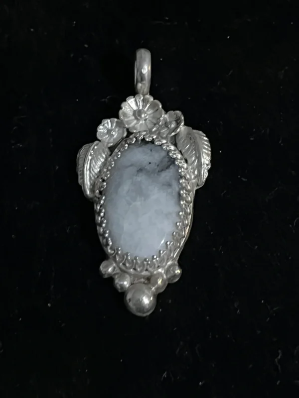 A silver pendant with a blue stone in the middle.