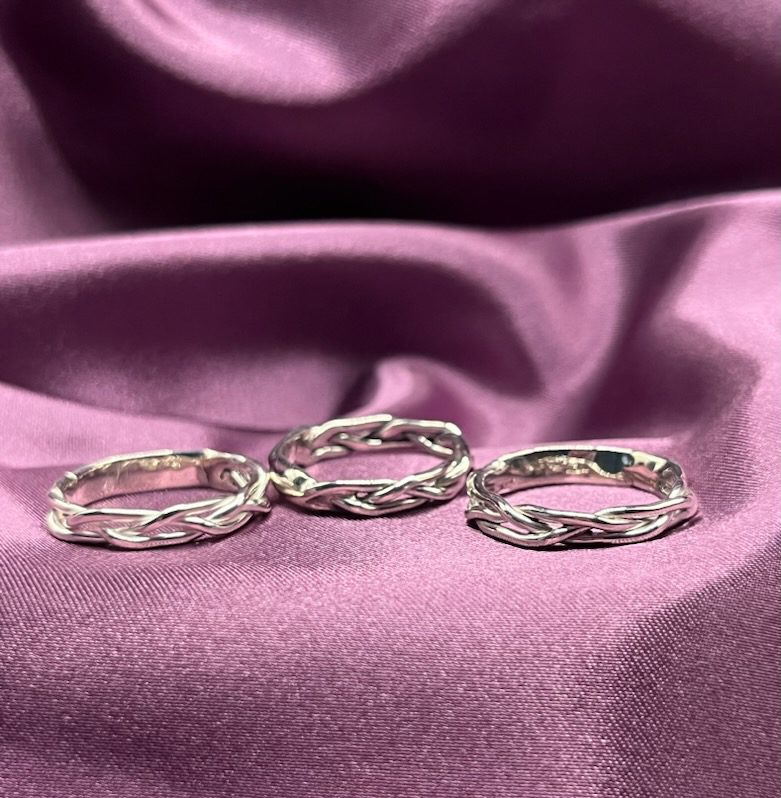 Three silver braided rings on fabric.